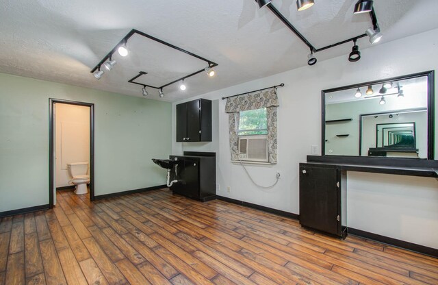 kitchen featuring a textured ceiling, dark wood-type flooring, and dark cabinets