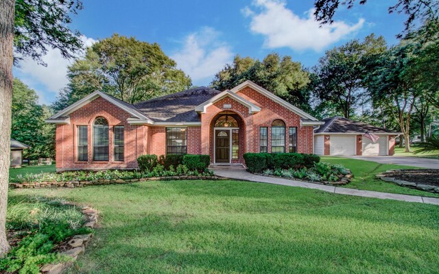 view of front of home with driveway, a front yard, a garage, and brick siding