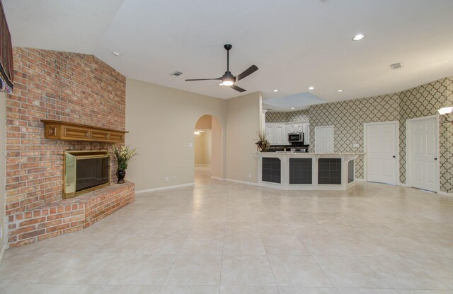 unfurnished living room featuring ceiling fan, light tile patterned flooring, and a brick fireplace