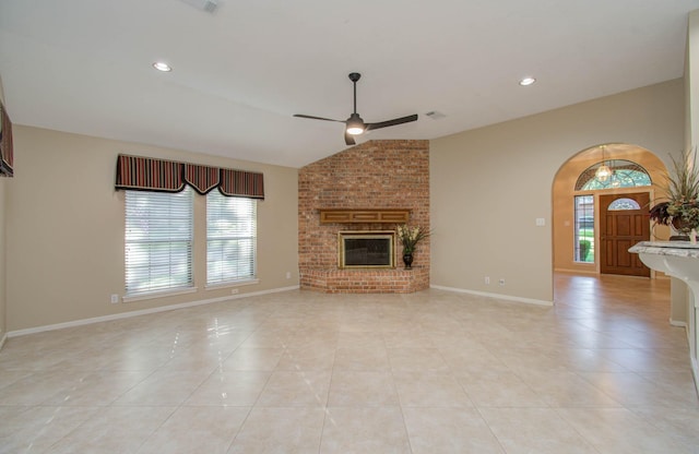 unfurnished living room with arched walkways, a brick fireplace, light tile patterned flooring, and lofted ceiling