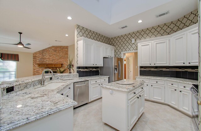 kitchen featuring kitchen peninsula, ceiling fan, appliances with stainless steel finishes, sink, and a center island