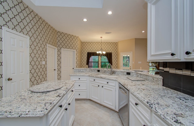 kitchen featuring sink, light stone countertops, pendant lighting, stainless steel dishwasher, and white cabinetry