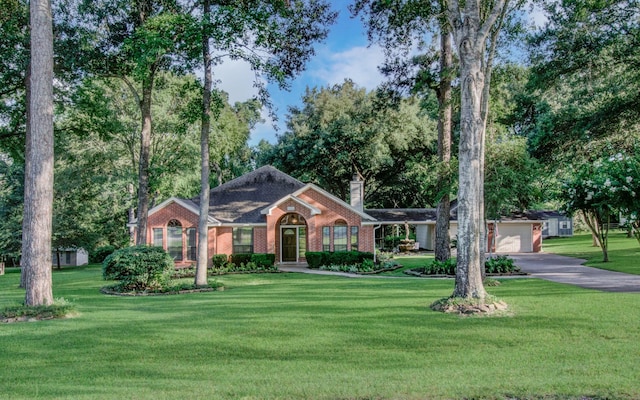 ranch-style house with aphalt driveway, a garage, brick siding, a chimney, and a front yard