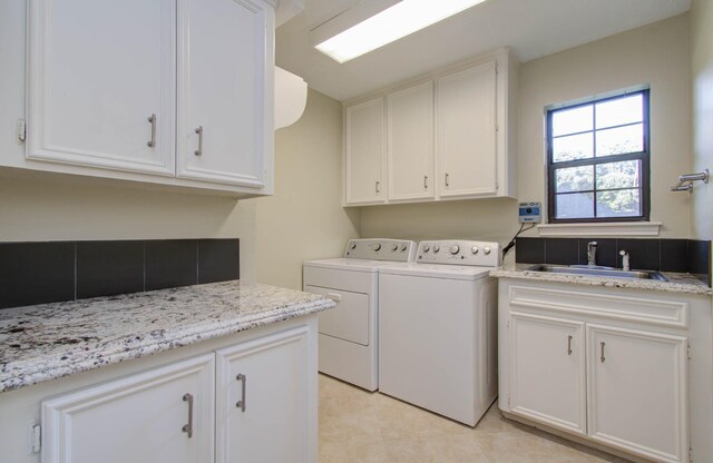 washroom featuring cabinets, sink, and washing machine and clothes dryer