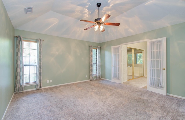 empty room featuring light carpet, visible vents, a ceiling fan, lofted ceiling, and french doors