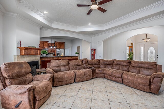 living room with crown molding, a tray ceiling, a textured ceiling, and light tile patterned floors