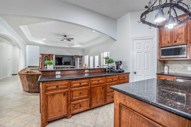 kitchen featuring hanging light fixtures, light tile patterned floors, ceiling fan, a tray ceiling, and a textured ceiling