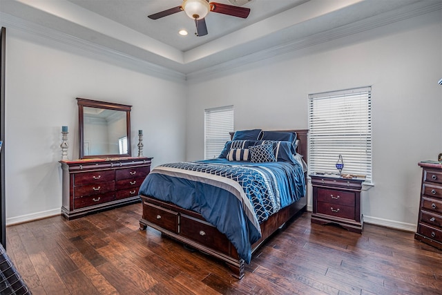 bedroom featuring dark hardwood / wood-style flooring, a tray ceiling, and ceiling fan