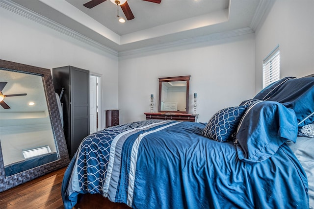 bedroom with hardwood / wood-style flooring, ornamental molding, ceiling fan, and a tray ceiling