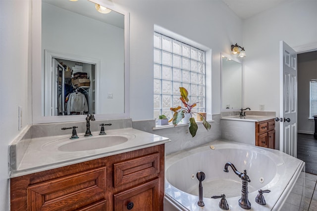 bathroom with vanity and tiled bath