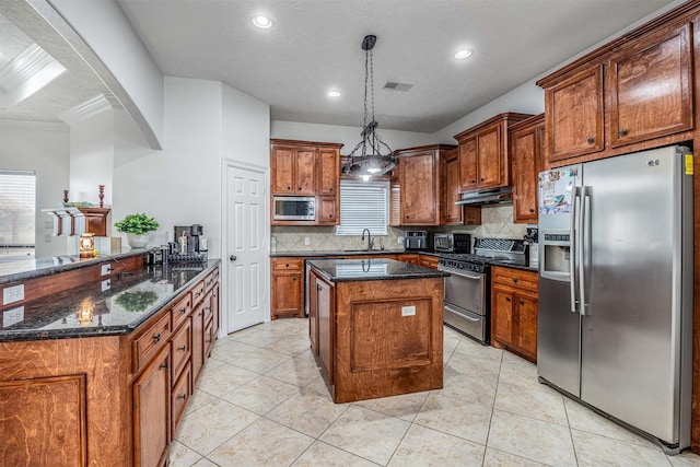 kitchen featuring hanging light fixtures, appliances with stainless steel finishes, backsplash, and dark stone counters