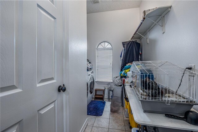 laundry area featuring washer / clothes dryer, a textured ceiling, and light tile patterned floors