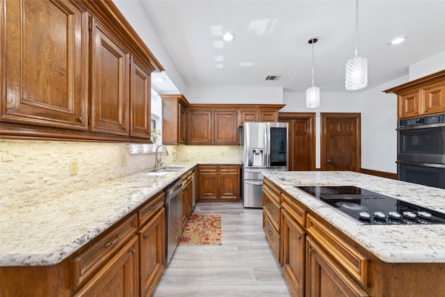 kitchen with backsplash, appliances with stainless steel finishes, light hardwood / wood-style flooring, sink, and decorative light fixtures