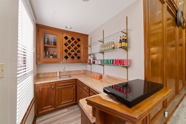 kitchen with light hardwood / wood-style floors, kitchen peninsula, and sink