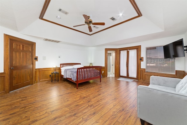 bedroom with ceiling fan, wood-type flooring, and a raised ceiling