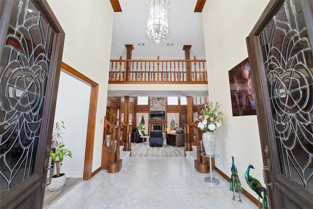 entryway featuring a high ceiling, a fireplace, and an inviting chandelier