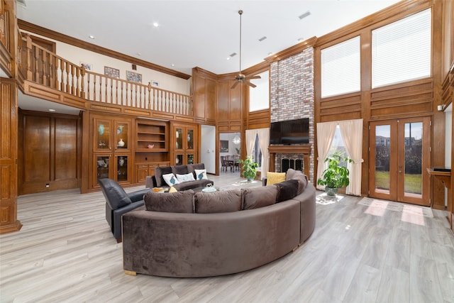 living room featuring a towering ceiling, a brick fireplace, ceiling fan, and a wealth of natural light