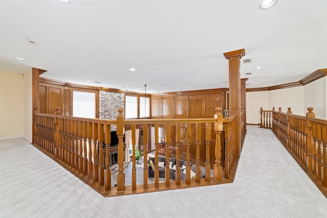 corridor with crown molding, light colored carpet, and decorative columns