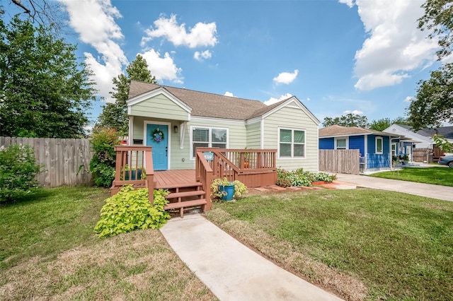 view of front of property with a front lawn, fence, a deck, and roof with shingles