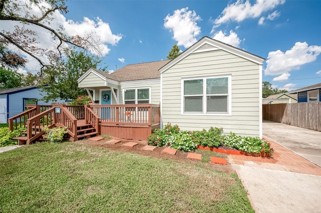 view of front facade with concrete driveway, fence, a deck, and a front yard
