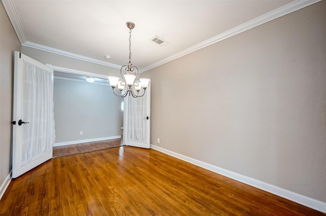 spare room featuring wood finished floors, visible vents, crown molding, and a notable chandelier