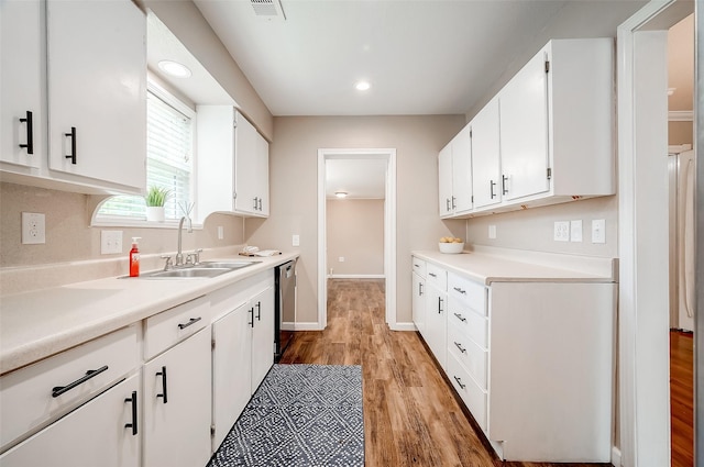 kitchen with visible vents, light wood finished floors, stainless steel dishwasher, and white cabinetry