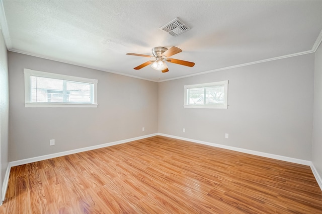 spare room with visible vents, a ceiling fan, light wood-style floors, crown molding, and baseboards