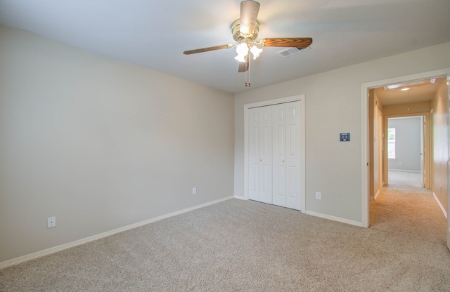 unfurnished bedroom with light colored carpet, a closet, and ceiling fan