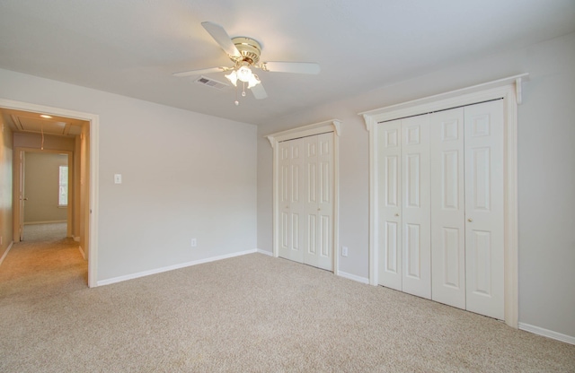 unfurnished bedroom featuring carpet floors, multiple closets, and ceiling fan