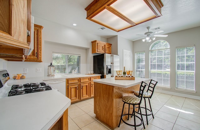 kitchen featuring a kitchen island, white dishwasher, stainless steel fridge, stove, and light tile patterned floors