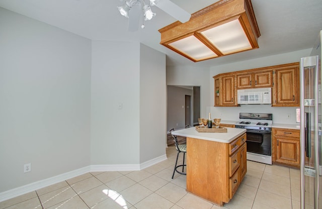 kitchen featuring white appliances, light tile patterned floors, a kitchen bar, and a kitchen island