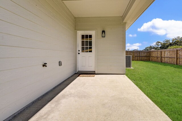 entrance to property featuring a patio, a lawn, and cooling unit