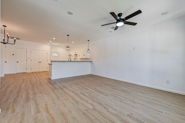 unfurnished living room featuring sink, ceiling fan with notable chandelier, and light wood-type flooring