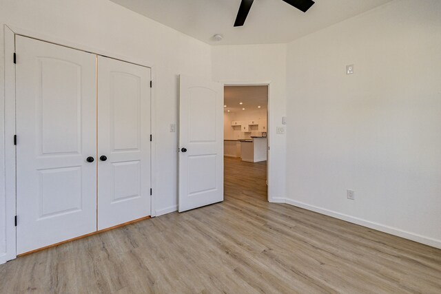 unfurnished bedroom featuring light hardwood / wood-style flooring, a closet, and ceiling fan