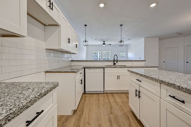 kitchen featuring white dishwasher, sink, decorative light fixtures, light wood-type flooring, and white cabinets