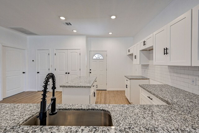 kitchen featuring light hardwood / wood-style flooring, light stone countertops, sink, and a kitchen island