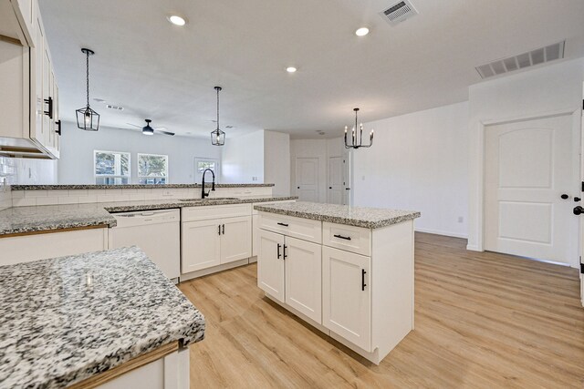 kitchen with a kitchen island, light hardwood / wood-style flooring, dishwasher, decorative light fixtures, and sink