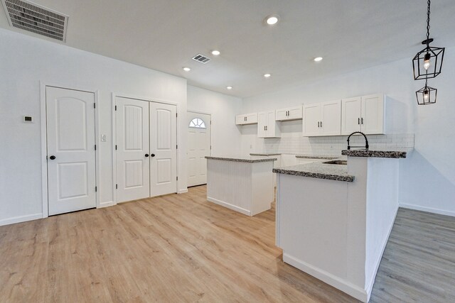 kitchen with sink, white cabinetry, pendant lighting, and light wood-type flooring