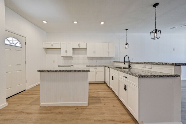 kitchen featuring white cabinetry, light hardwood / wood-style flooring, sink, and pendant lighting