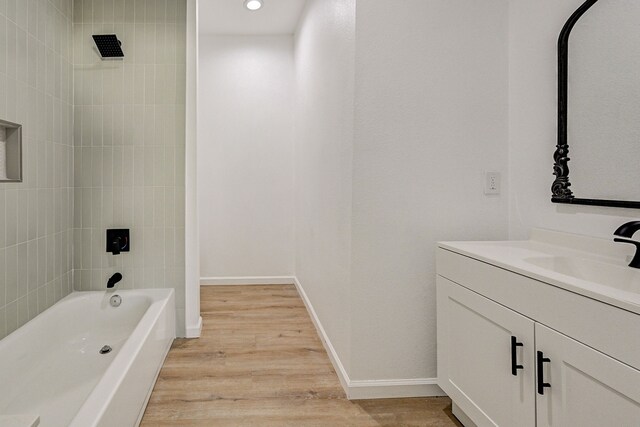 bathroom with tiled shower / bath, vanity, and wood-type flooring