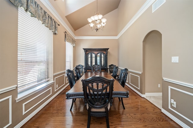 dining room with a chandelier, hardwood / wood-style floors, high vaulted ceiling, and crown molding