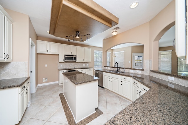 kitchen with tasteful backsplash, stainless steel appliances, sink, dark stone countertops, and white cabinetry