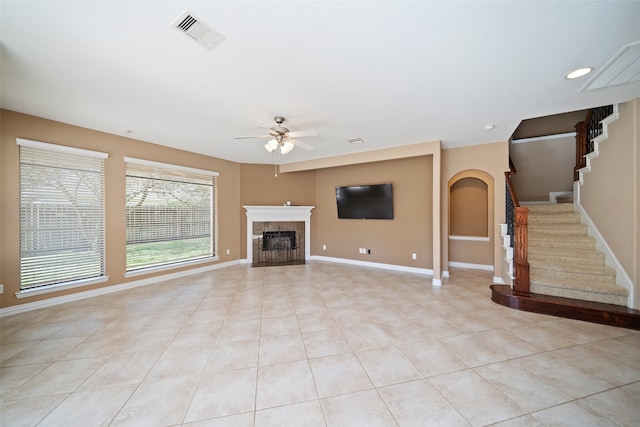 unfurnished living room featuring ceiling fan, light tile patterned floors, and a tile fireplace