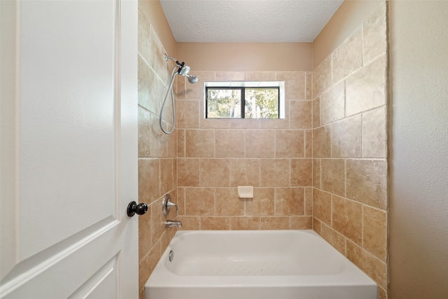 bathroom featuring a textured ceiling and tiled shower / bath combo