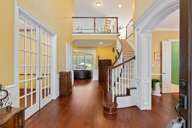 foyer entrance with french doors, crown molding, dark hardwood / wood-style floors, and a towering ceiling