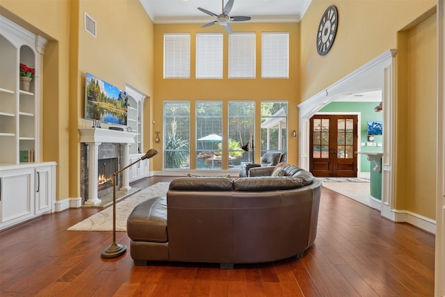 living room featuring a fireplace, french doors, ceiling fan, dark wood-type flooring, and ornamental molding