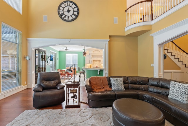 living room featuring a high ceiling, wood-type flooring, and ceiling fan