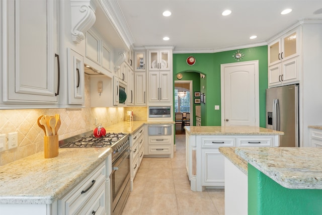 kitchen with light stone countertops, a center island, stainless steel appliances, and white cabinets