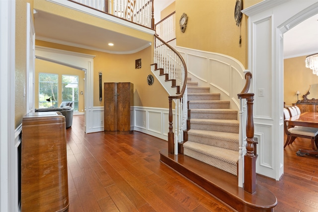 stairs featuring hardwood / wood-style flooring, ornamental molding, and an inviting chandelier