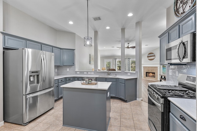 kitchen with sink, a center island, appliances with stainless steel finishes, a fireplace, and tasteful backsplash